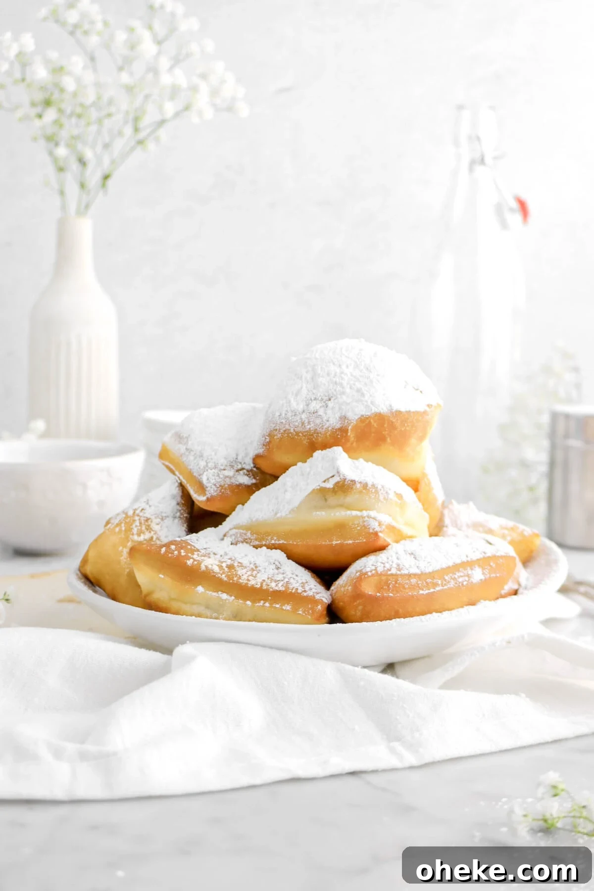 front shot of beignets in bowl with flower and white napkin