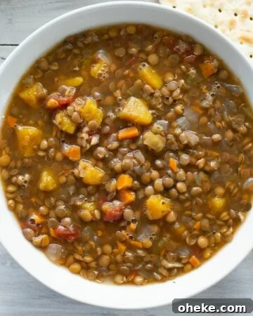 Soup bowl filled with lentil butternut squash soup with a yellow napkin in the background.