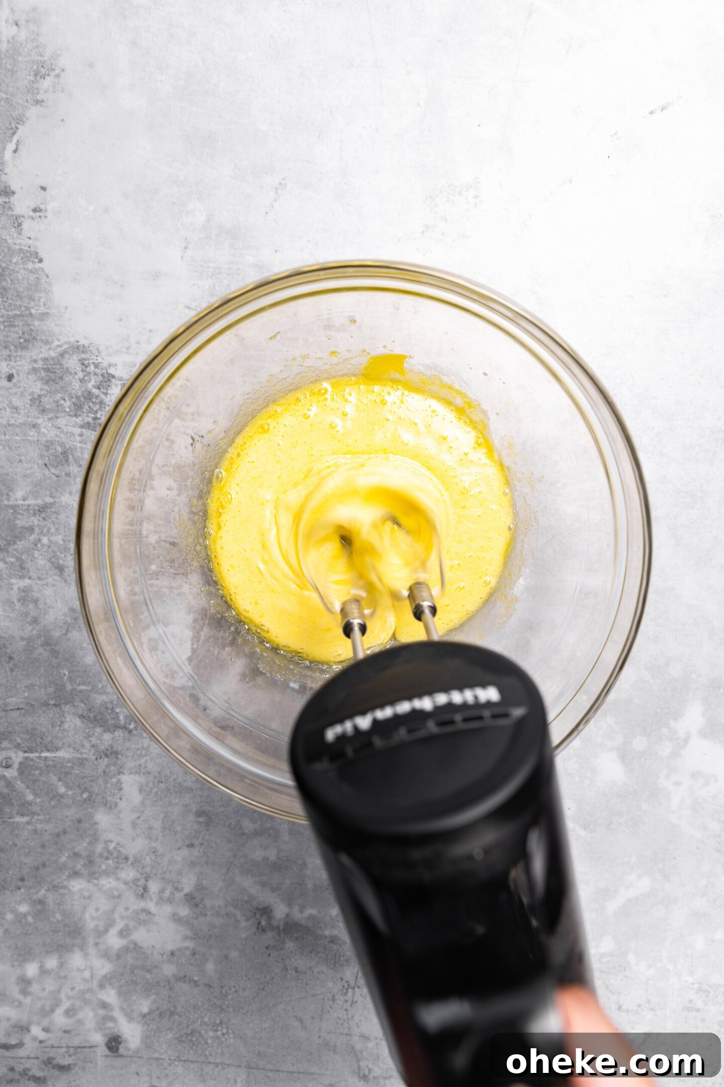 Eggs and sugar being whipped in a mixing bowl.