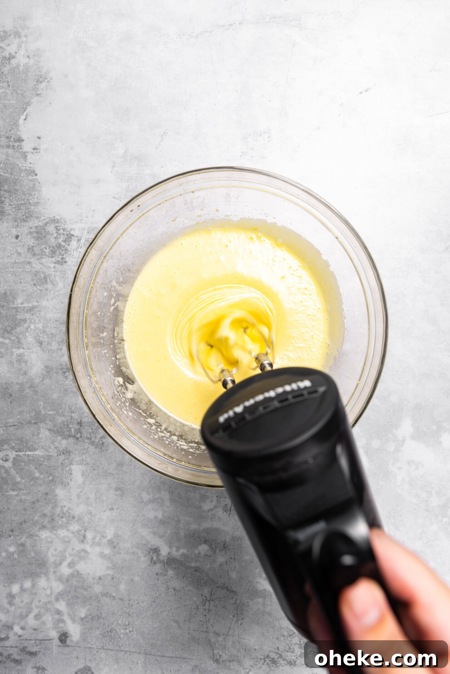 Butter and sugar syrup mixture being beaten into egg mixture.