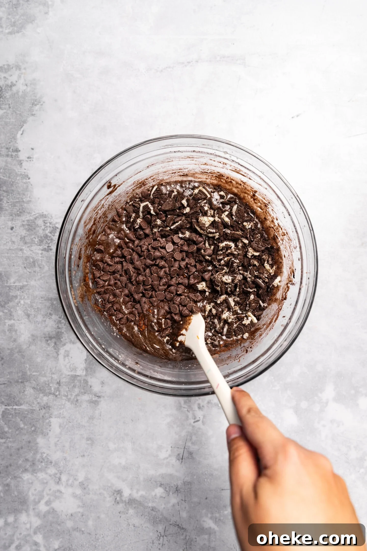 Chocolate chips and oreos being incorporated into the brownie batter.