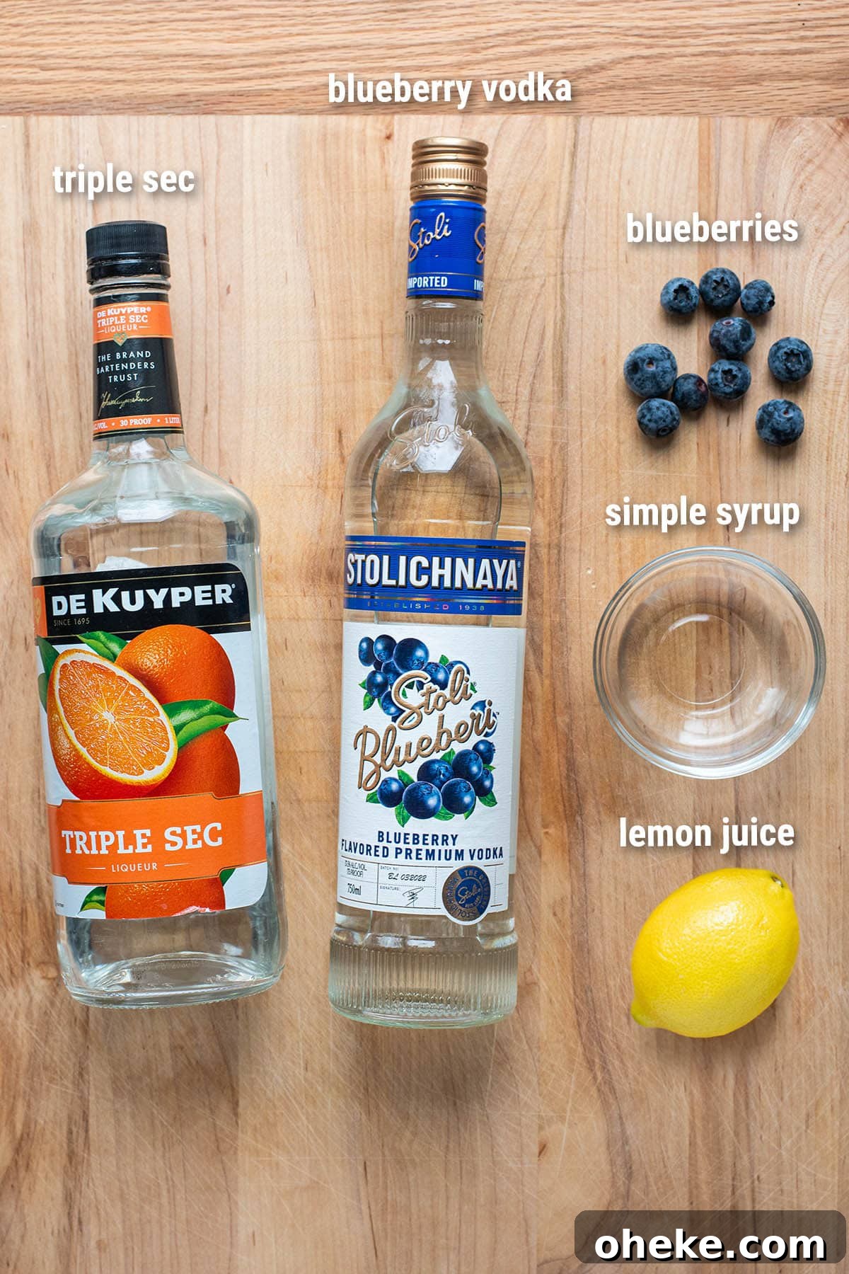 Blueberry Martini Recipe: How to Make a Refreshing Blueberry Cocktail 3 Blueberry martini ingredients laid out on a wooden cutting board.