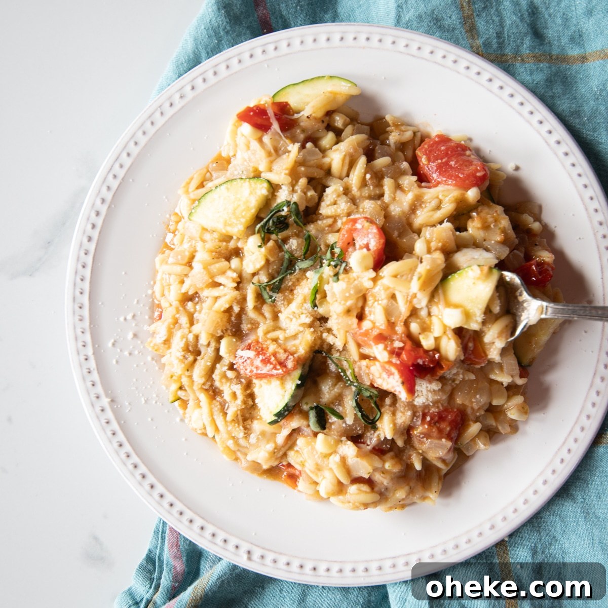 September Week 2 Vegetarian Meal Plan: Fresh Recipes & Grocery List 7 One-pot pasta dish of tomatoes, zucchini, corn, pesto, and mozzarella mixed into orzo on a white plate.