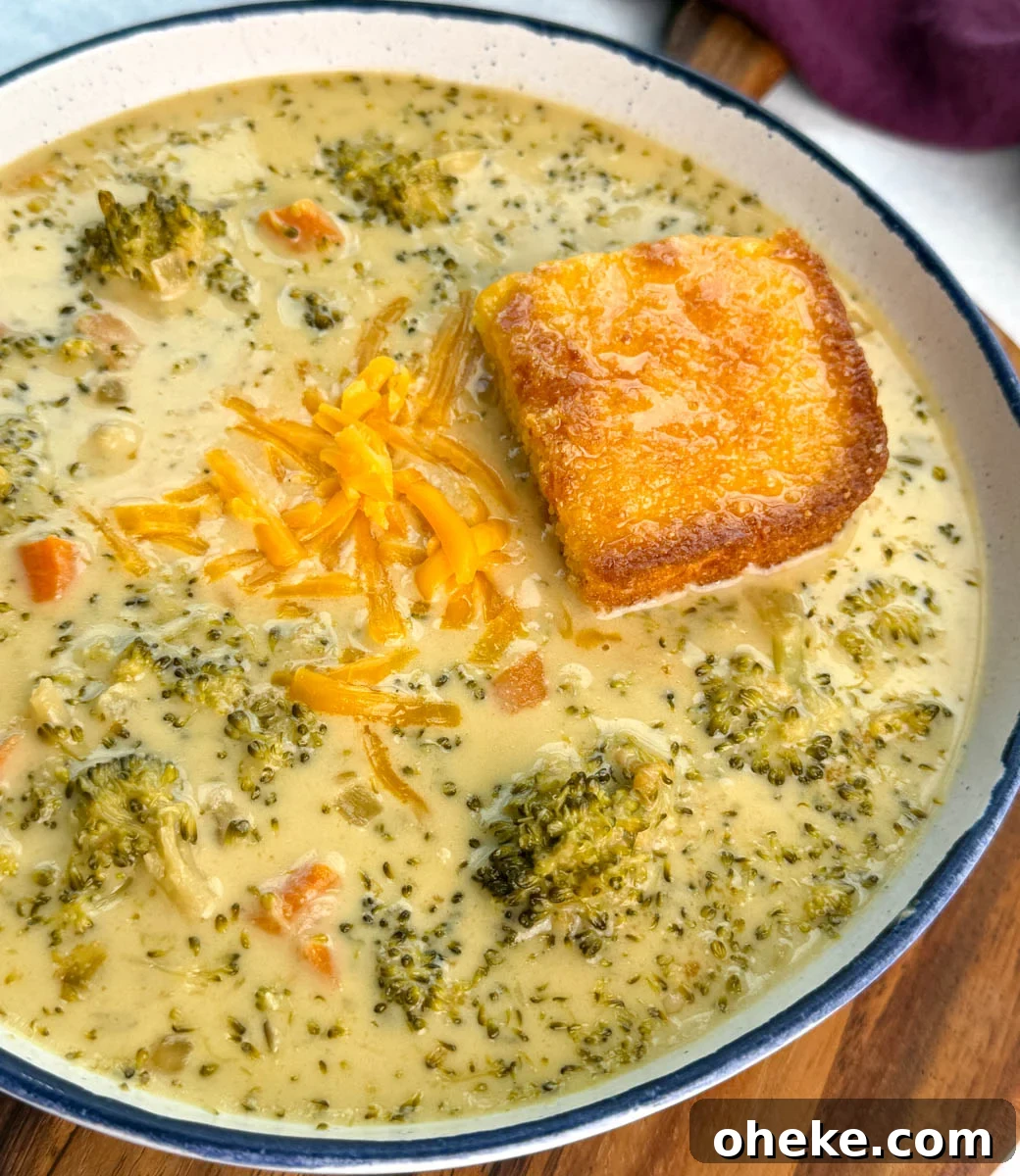 Slow Cooker Broccoli Cheddar Soup (Crockpot Recipe) 5 Bowl of broccoli cheddar soup topped with shredded cheddar cheese and served with a square of golden cornbread on the side.
