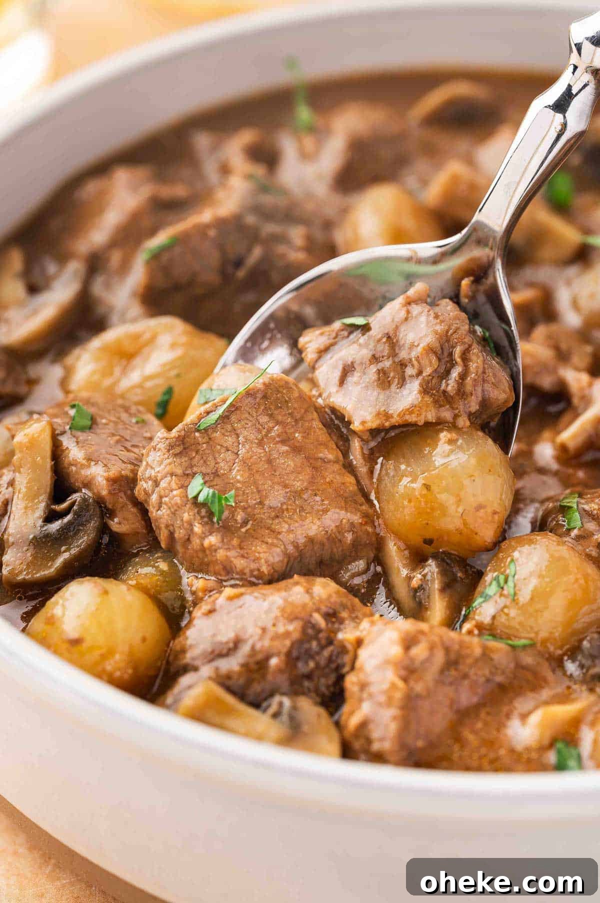A close up view of a spoonful of slow cooker beef tips and gravy lifted from a bowl.