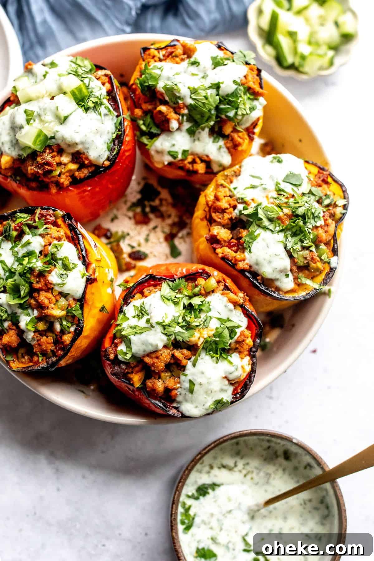 Mediterranean Stuffed Peppers with Ground Turkey and Feta 2 Ground turkey stuffed Peppers in a grey bowl with gold forks and plates on the side.