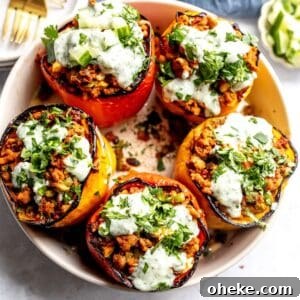 Mediterranean Stuffed Peppers with Ground Turkey and Feta 10 Ground turkey stuffed Peppers in a grey bowl with gold forks and plates on the side.