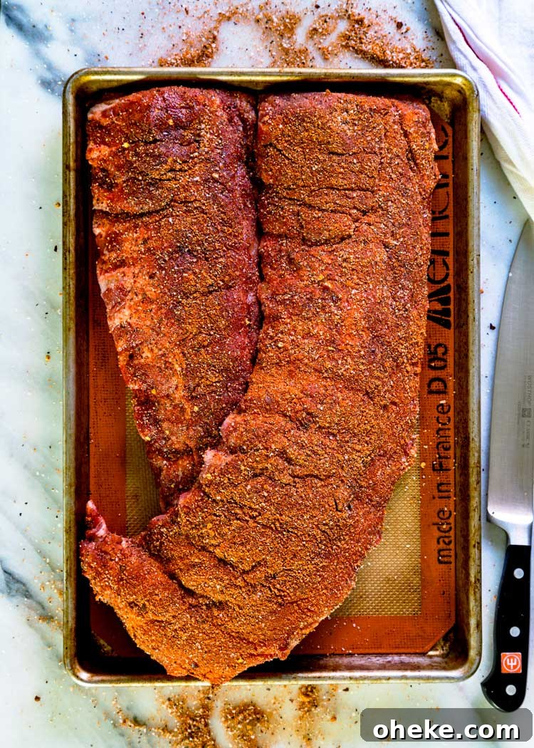 2 racks of baby back ribs rubbed with seasoning on baking sheet