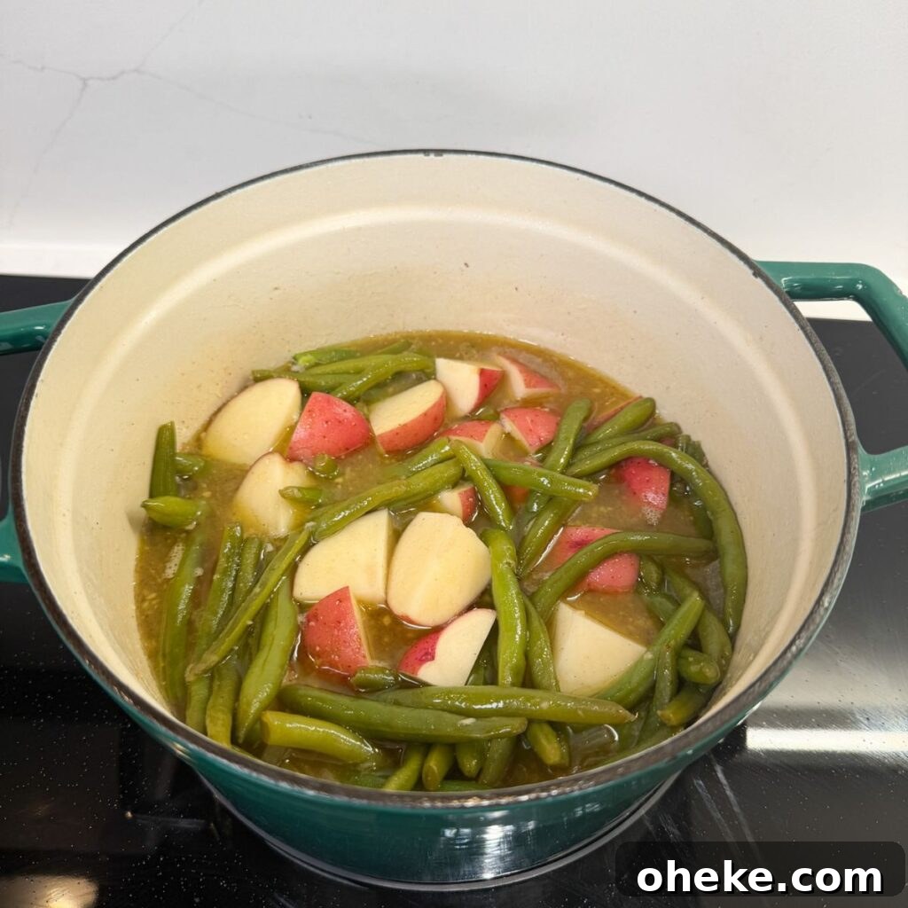 Southern-Style Green Beans and Potatoes Recipe for Comforting Sides 12 Green beans and potatoes in a pot with broth.