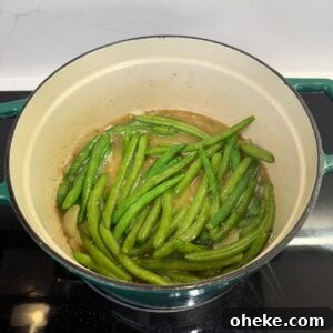 Southern-Style Green Beans and Potatoes Recipe for Comforting Sides 7 Green beans simmering in a dutch oven.