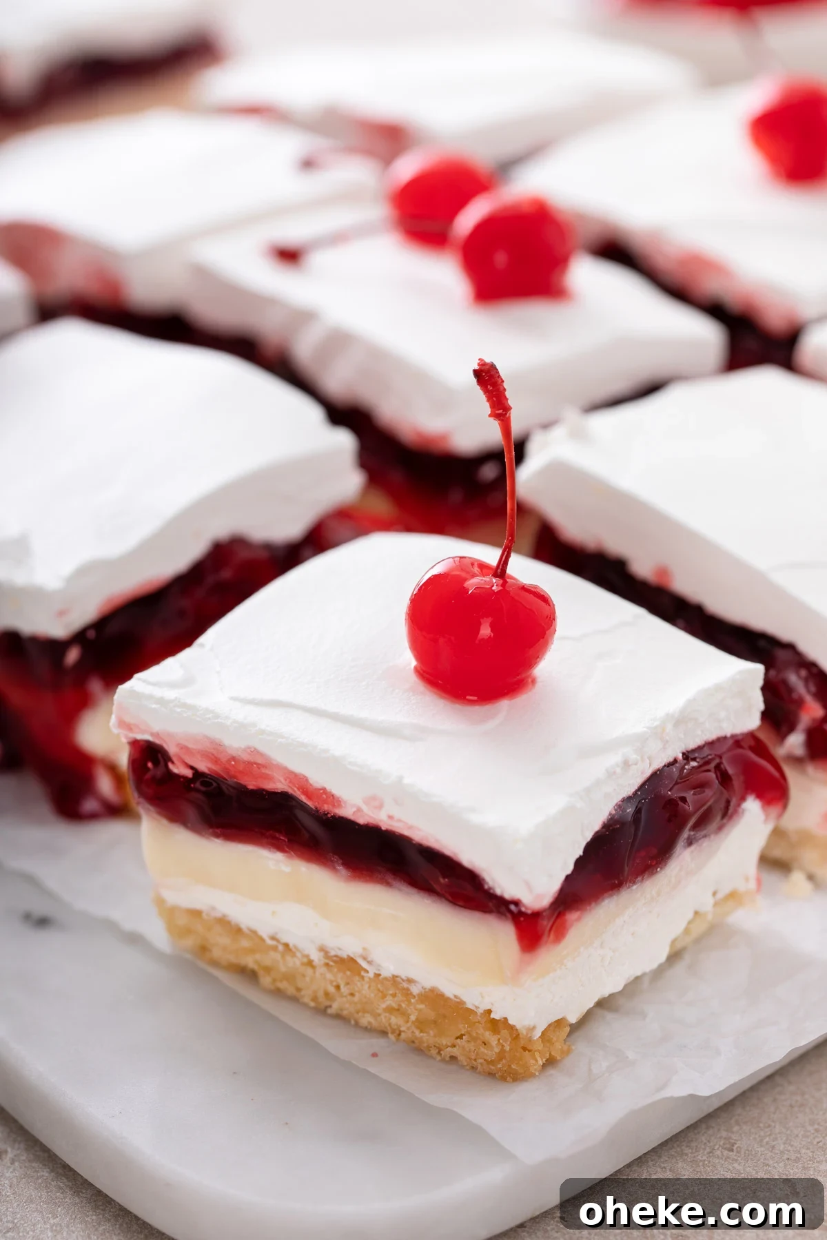 Close up of a slice of layered cherry cheesecake dessert on a platter of slices of the dessert.