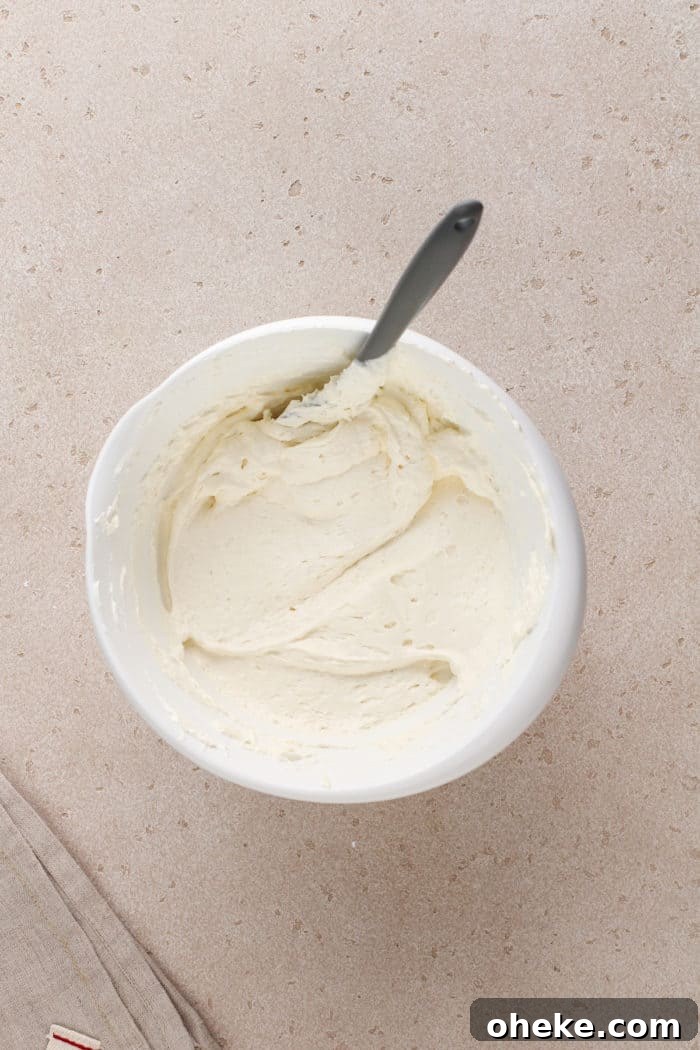 Cream cheese layer for cherry cheesecake dessert mixed in a white bowl.