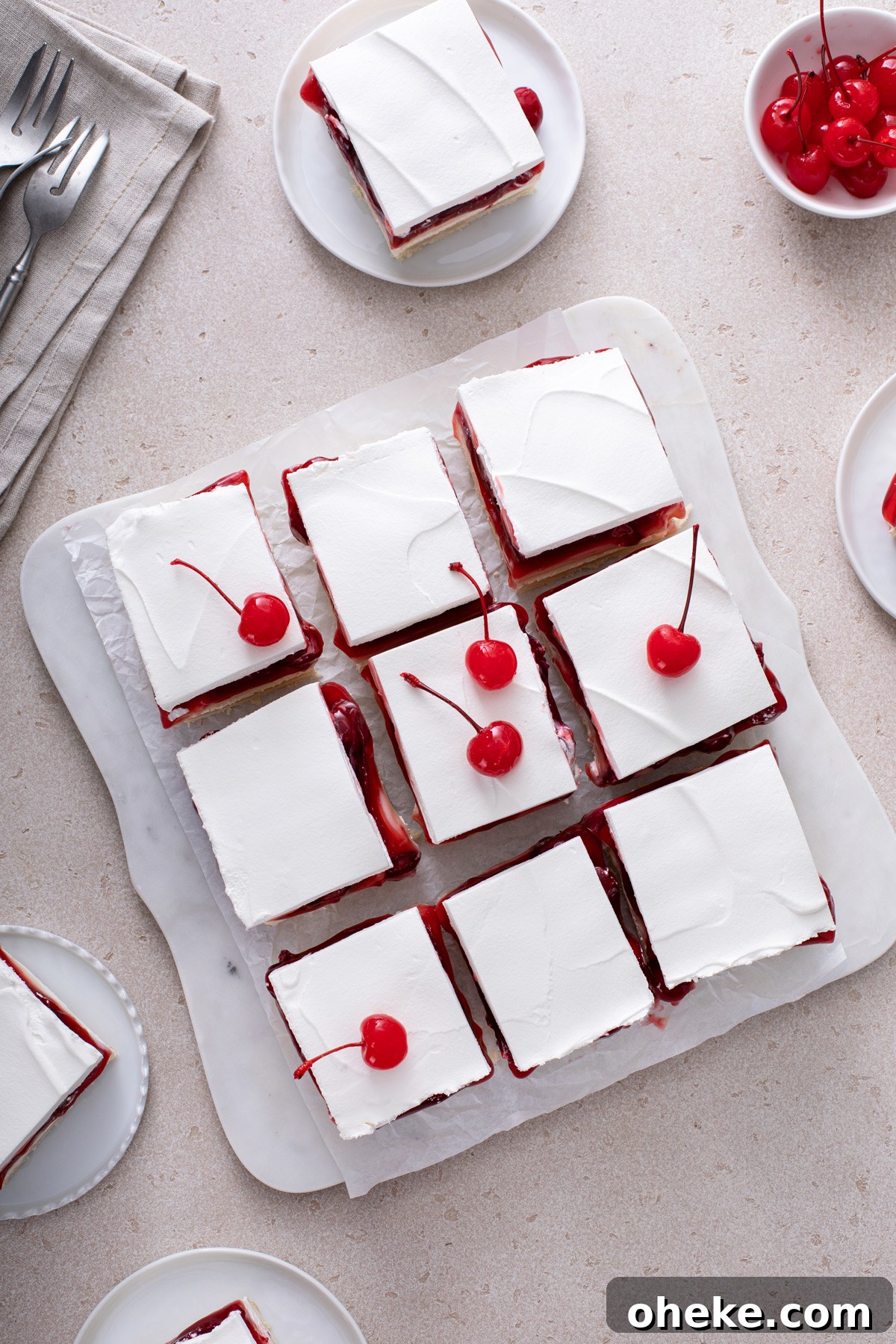 Overhead view of slices of layered cherry cheesecake dessert garnished with maraschino cherries.