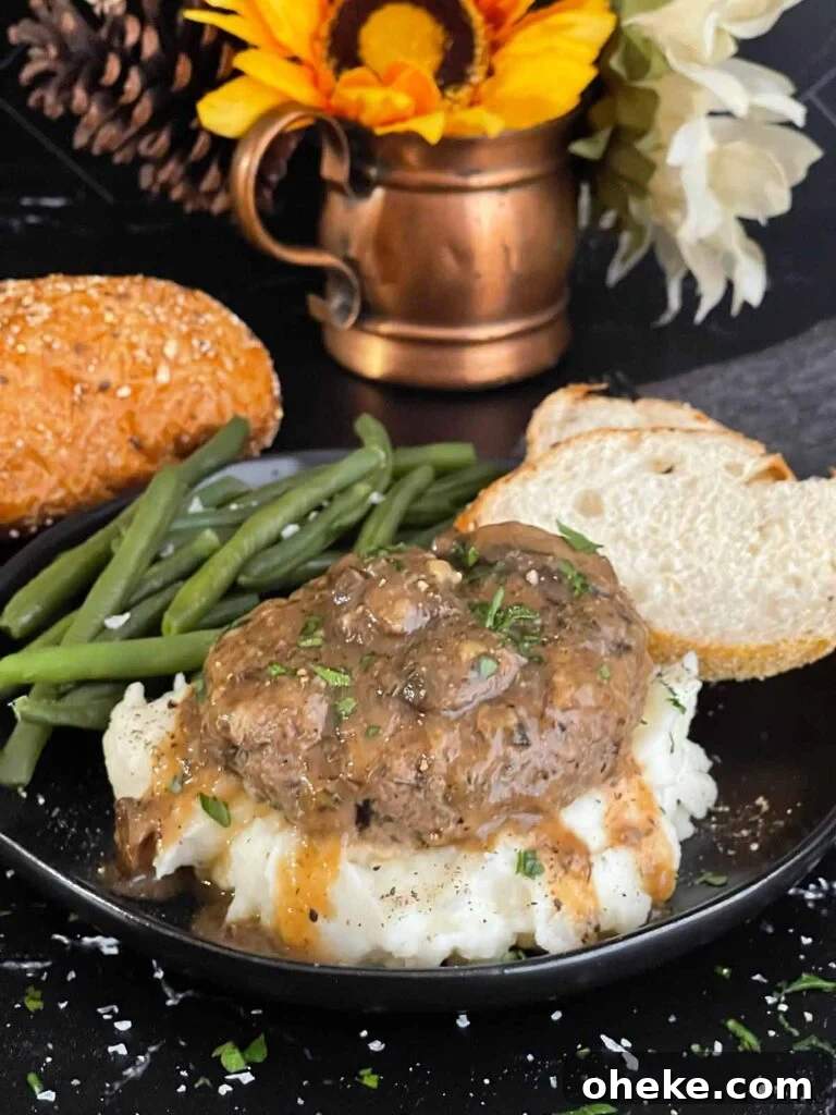 Close-up of Salisbury steak with mushroom gravy pouring over mashed potatoes