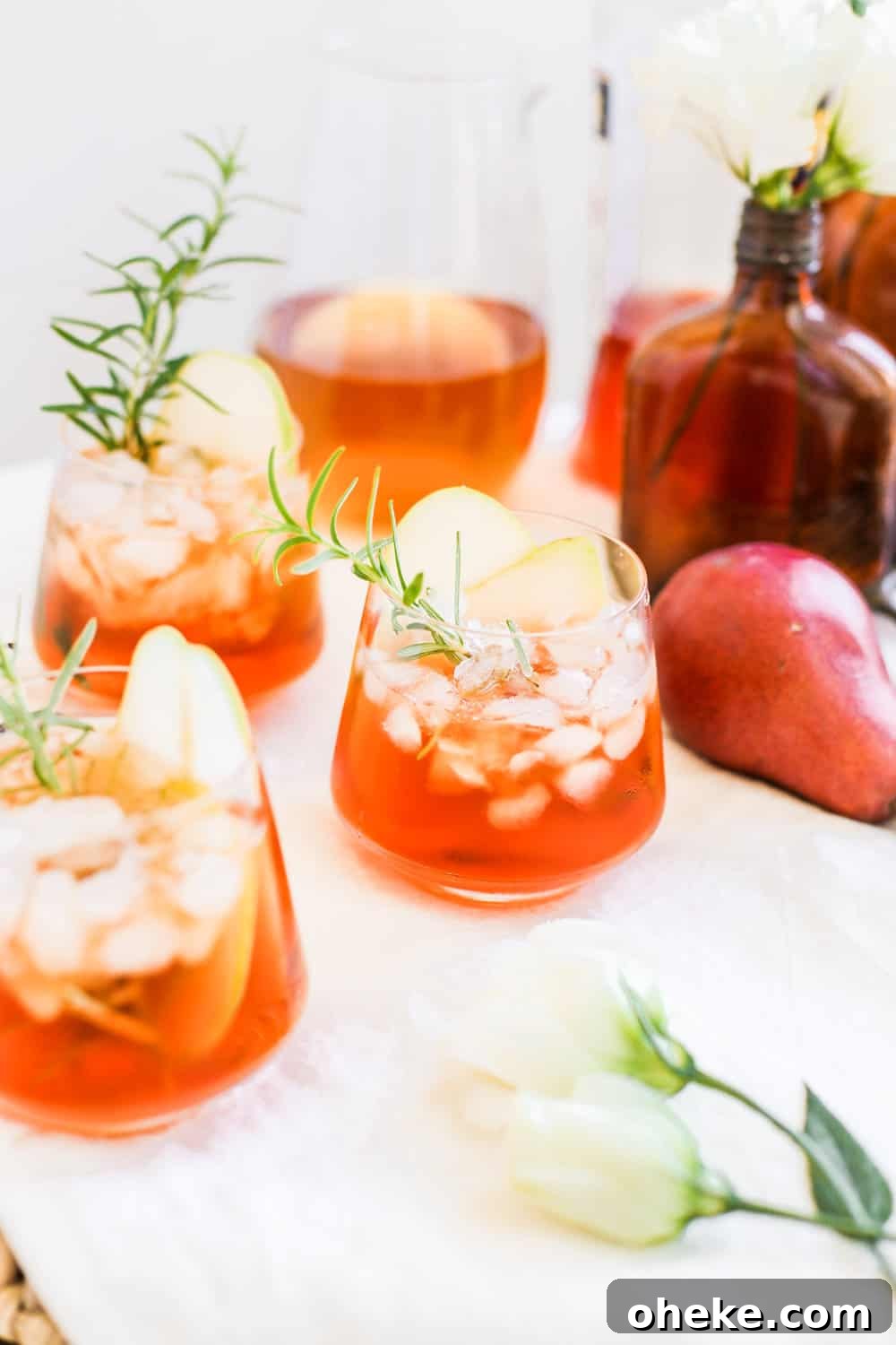A low clear glass filled with aperol and hard cider with a rosemary sprig.