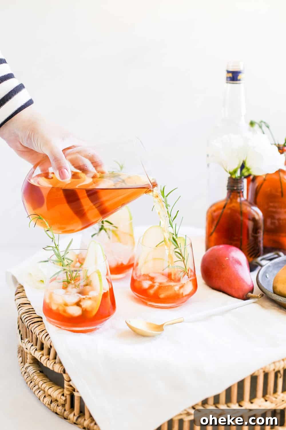 Apple juice being poured into a low clear glass on a serving tray.