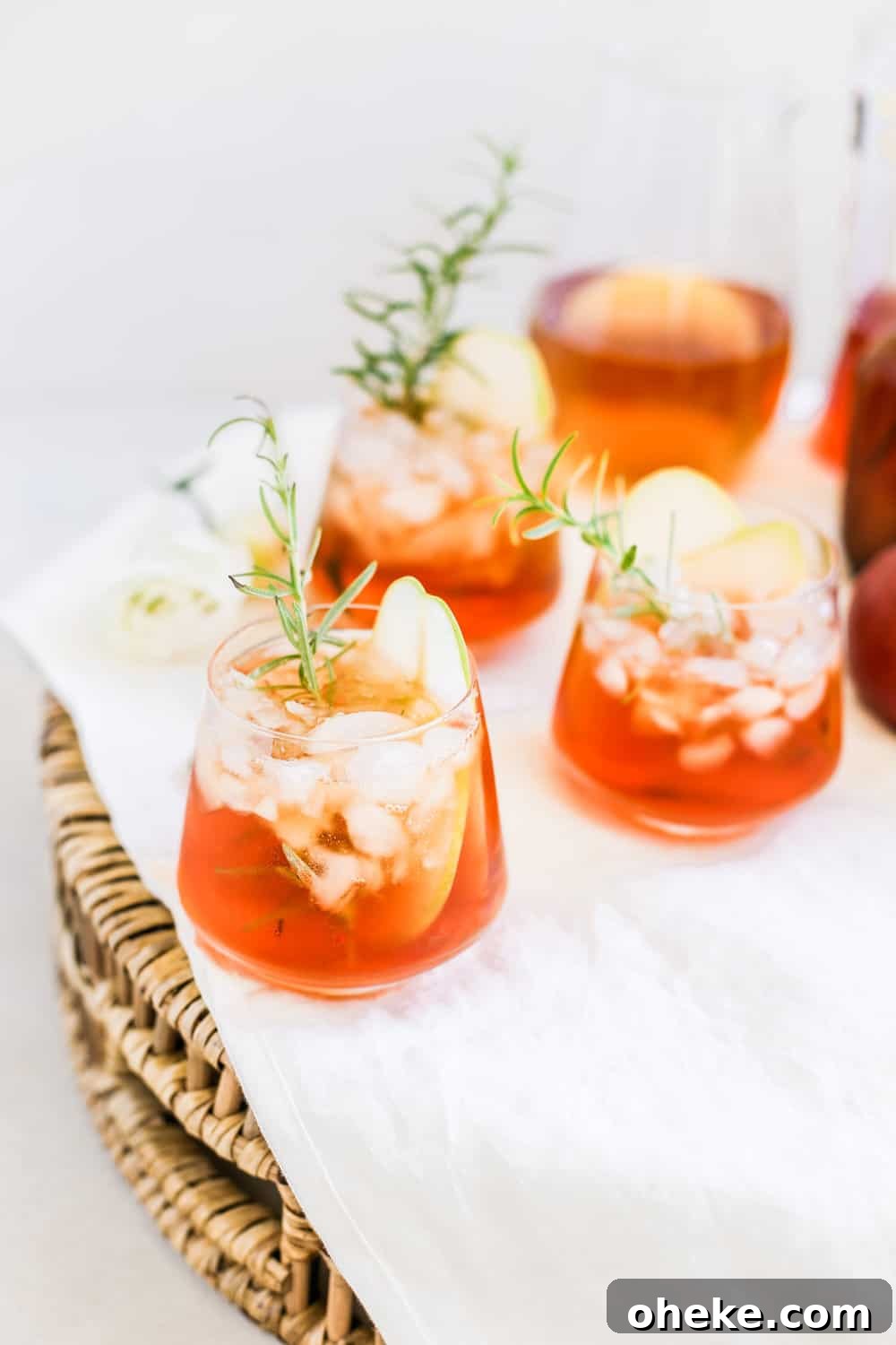 A low clear glass filled with aperol and hard cider with a rosemary sprig.