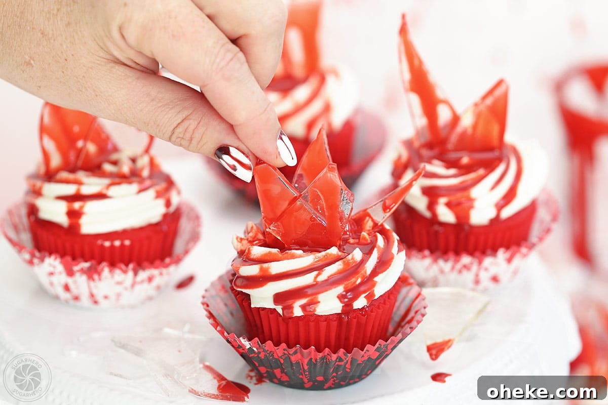 Bloody Glass Cupcakes Recipe: Spooky Jello-Filled Treats for Halloween 26 Hand placing a piece of glass on top of a bloody glass cupcake.