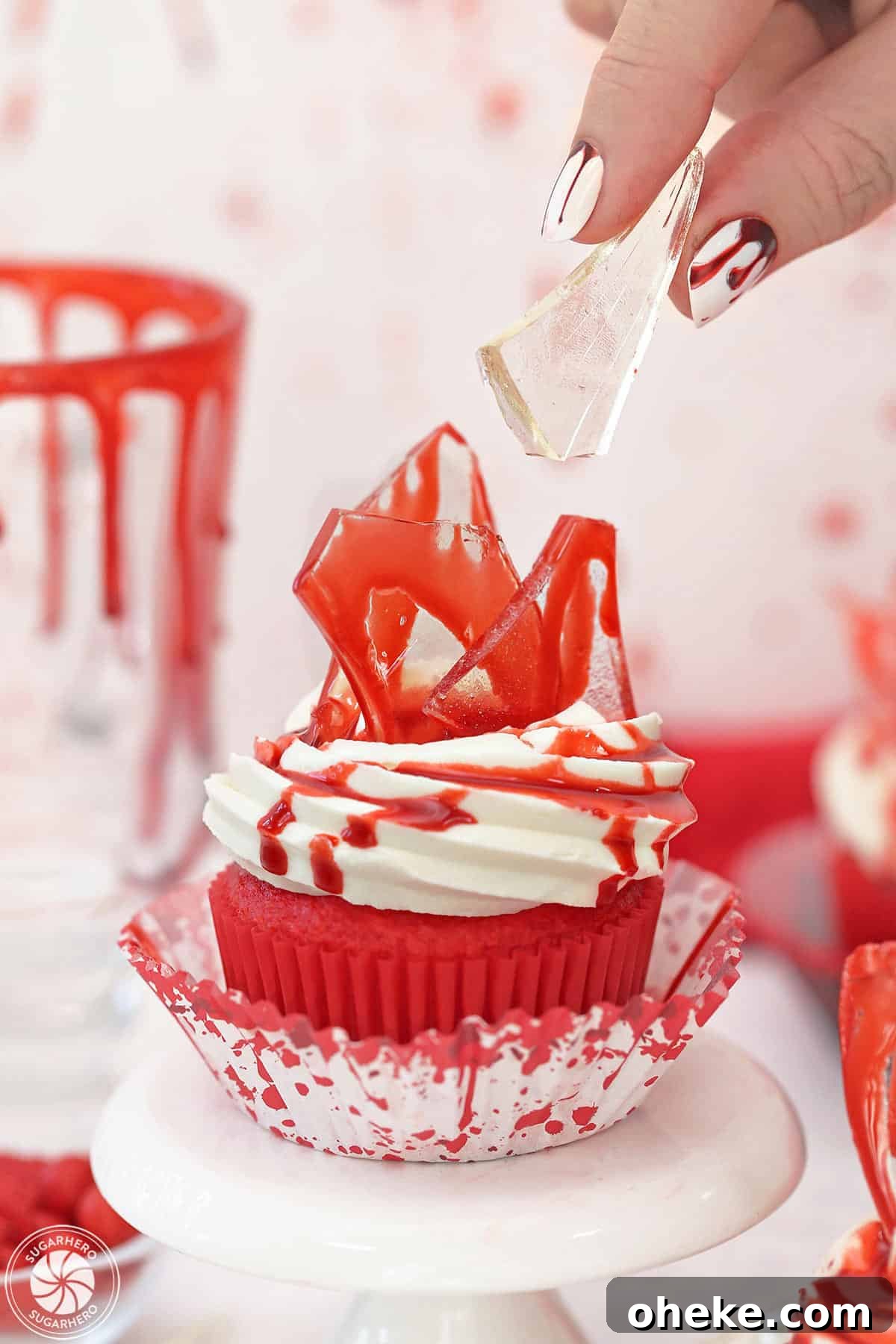 Bloody Glass Cupcakes Recipe: Spooky Jello-Filled Treats for Halloween 5 Hand placing a piece of edible glass on top of a bloody glass cupcake.