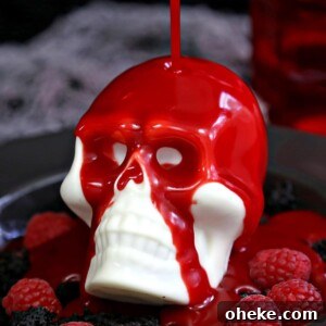 Bloody Glass Cupcakes Recipe: Spooky Jello-Filled Treats for Halloween 10 Raspberry ganache being poured over white chocolate skull.