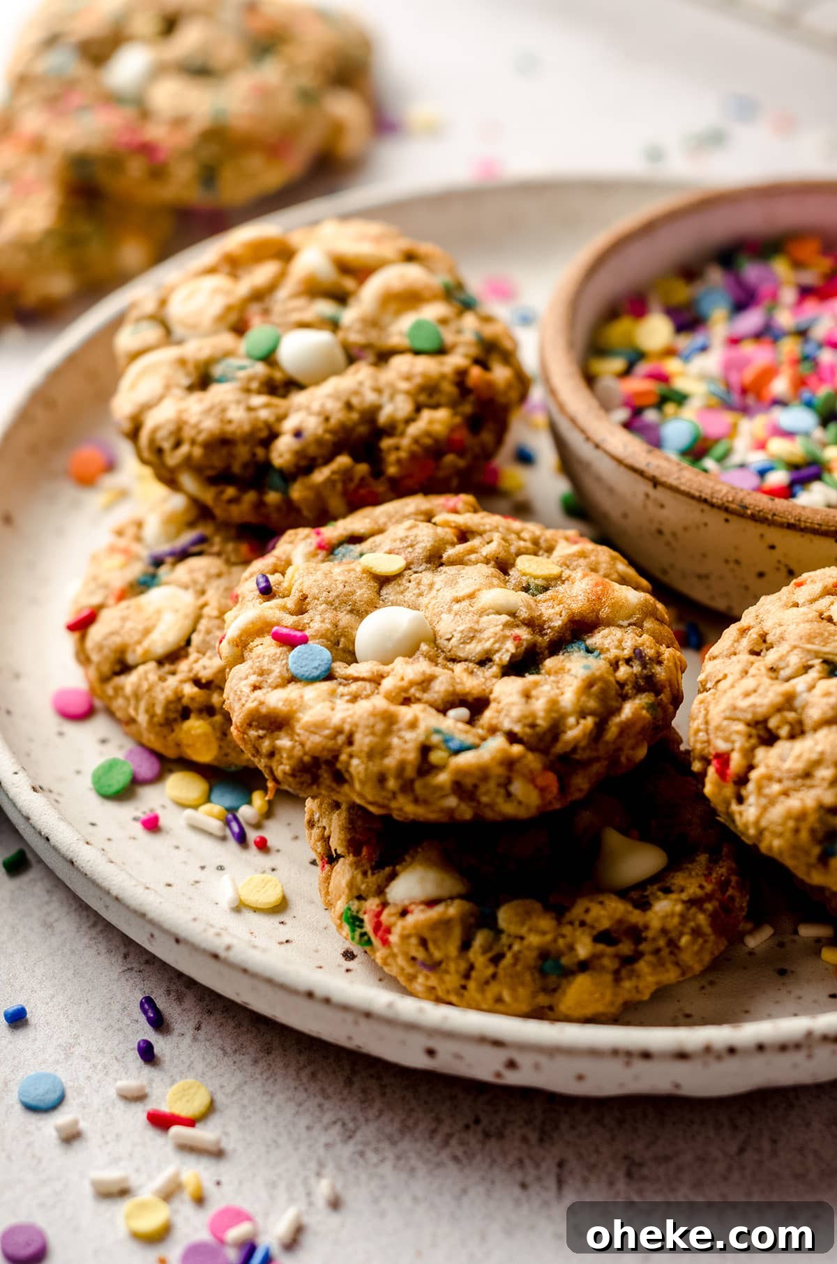 Funfetti White Chocolate Oatmeal Cookies Recipe 4 funfetti oatmeal cookies on a plate with a bowl of sprinkles