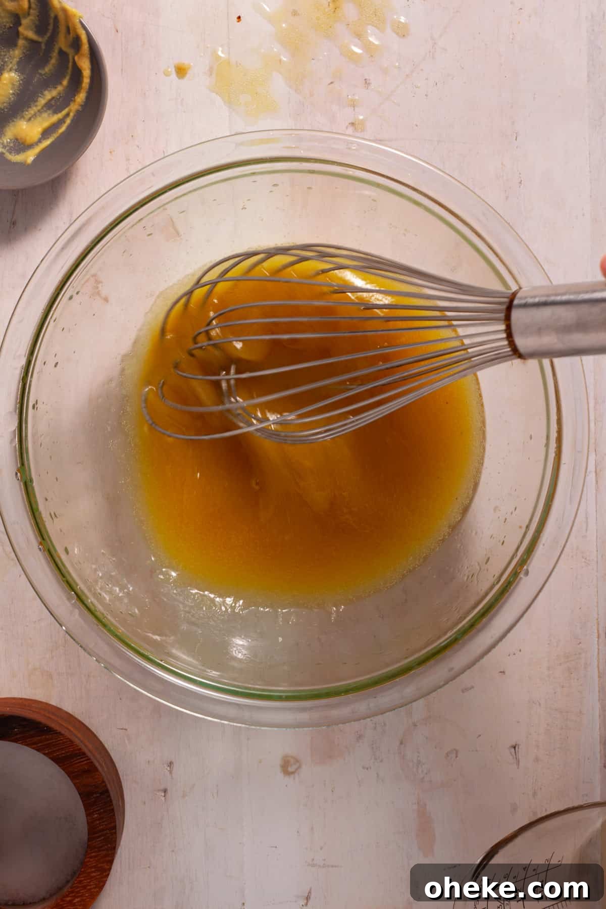 Oil whisked into a bowl with ingredients to make a maple Dijon dressing.