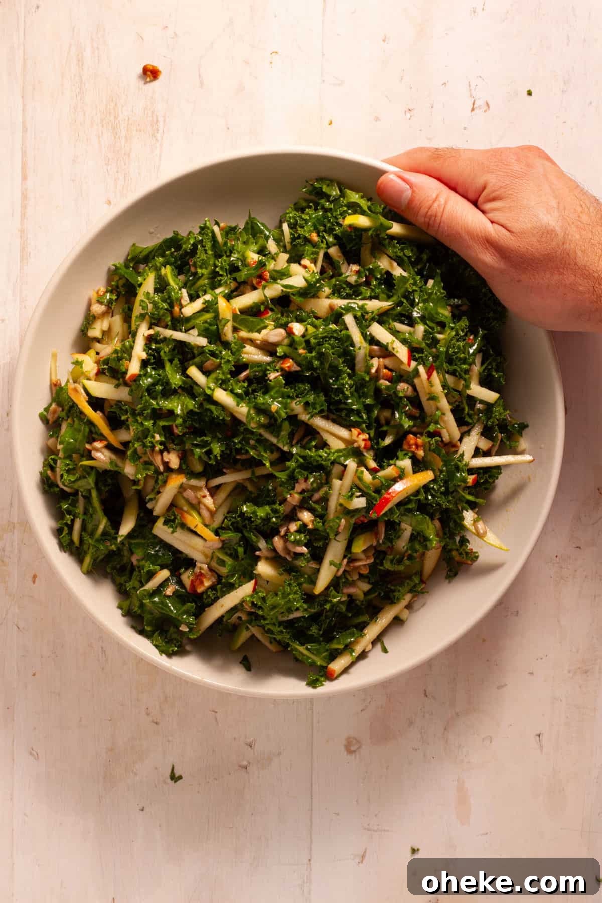 Kale and Apple Slaw topped with maple Dijon dressing in a serving bowl.