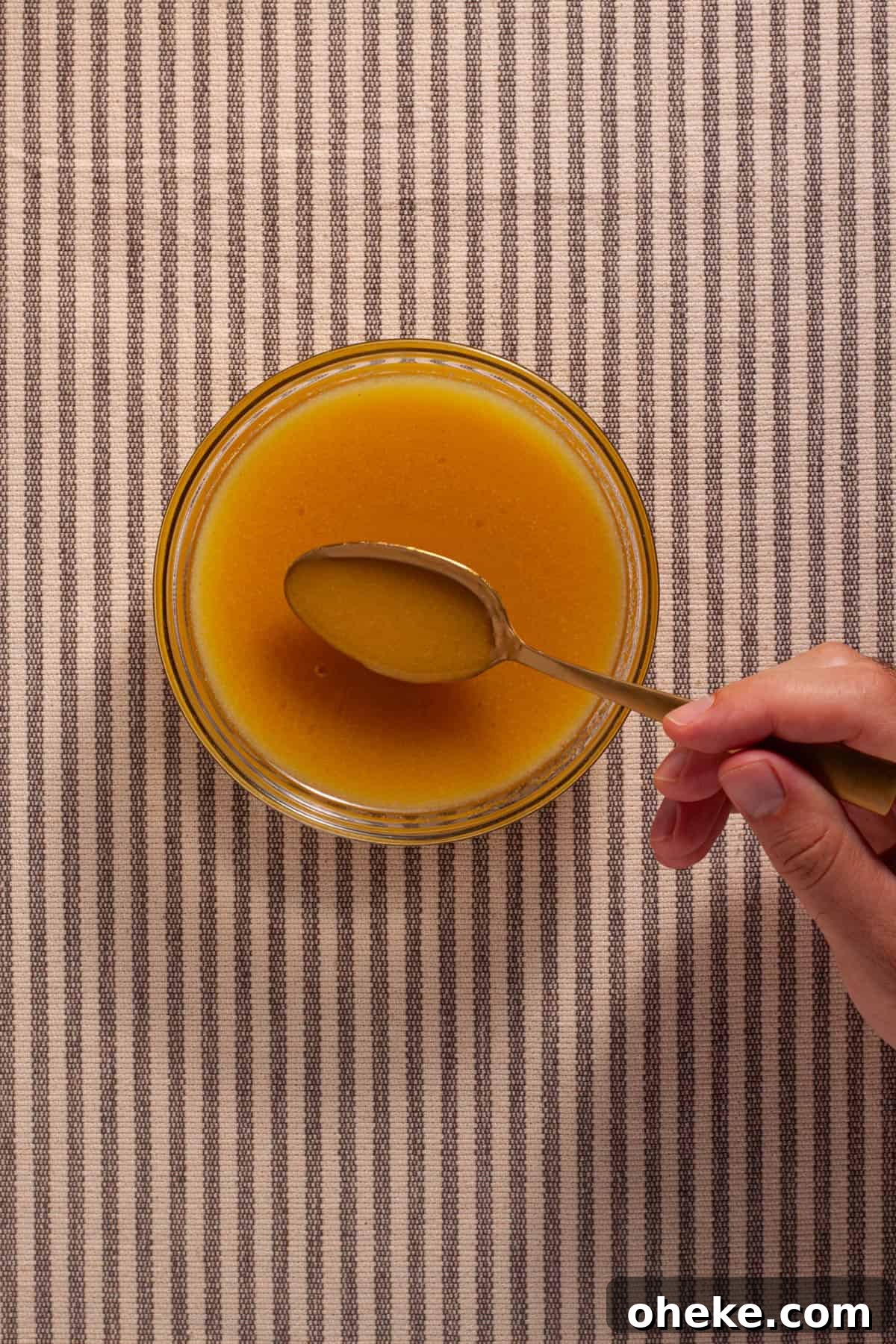 Maple Dijon Dressing in a small bowl with a spoon inside.