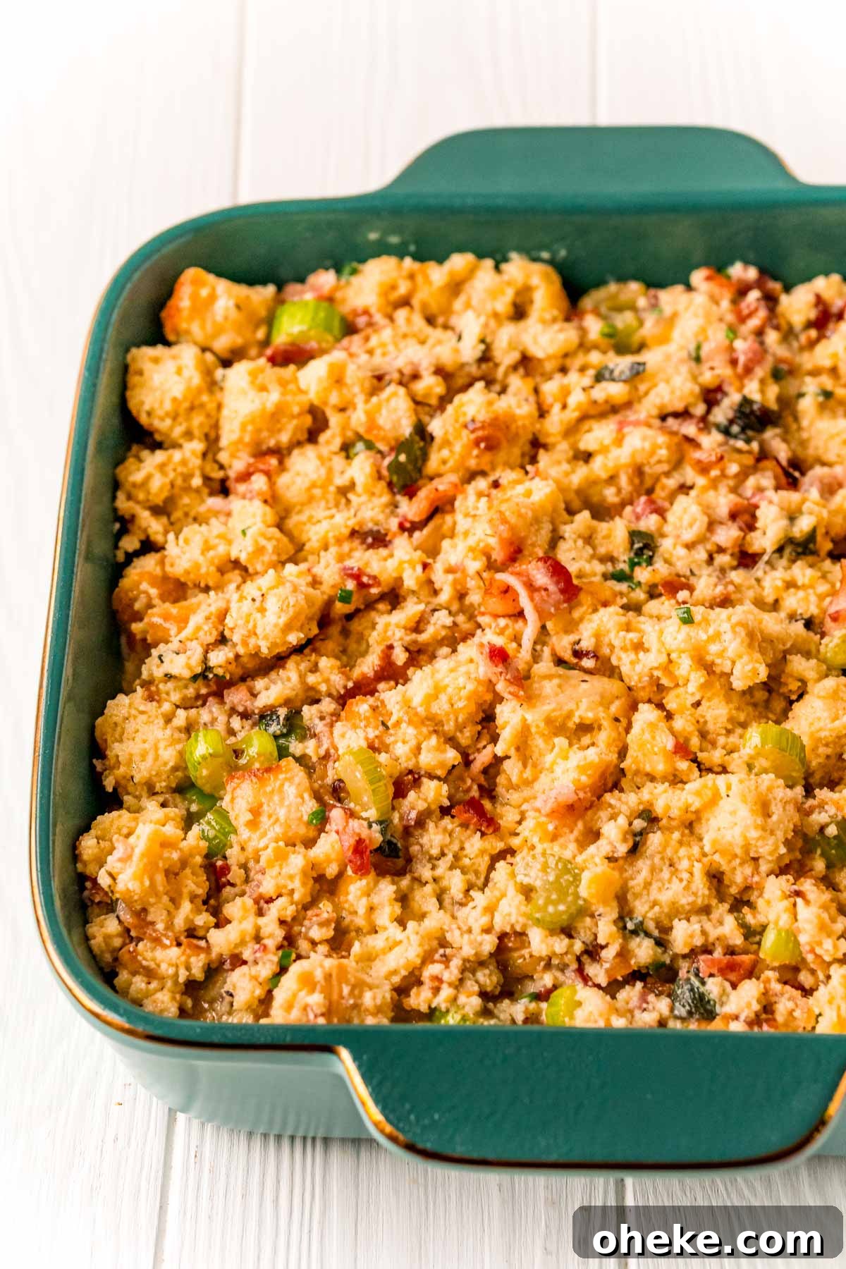 Cornbread stuffing mixture in a teal baking dish ready to be baked.