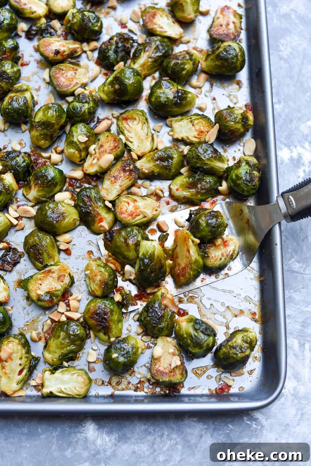 A spatula lifts some of the Brussels sprouts from the baking sheet.