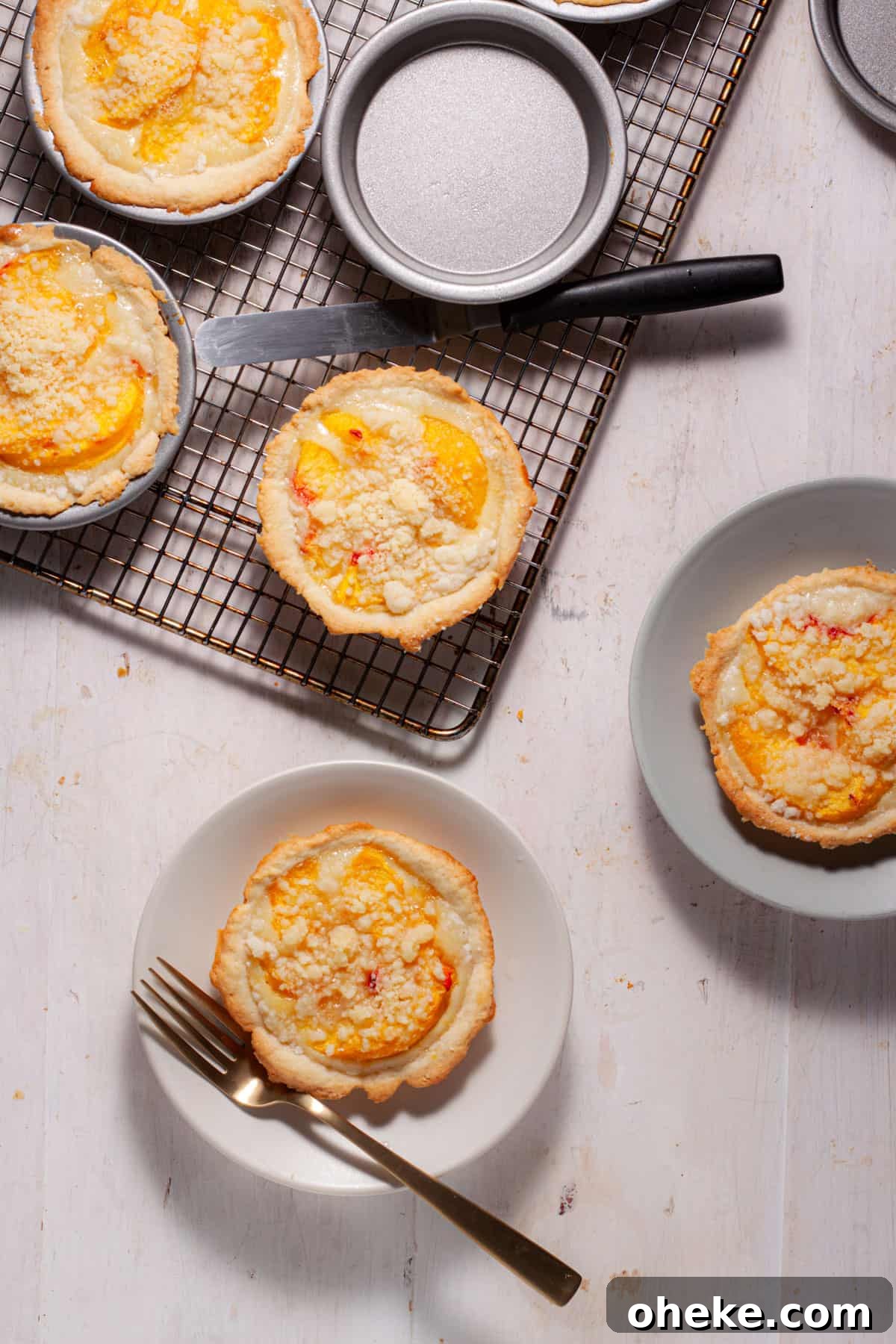 Mini peach custard pies cooling on a rack with a portion on a small plate.