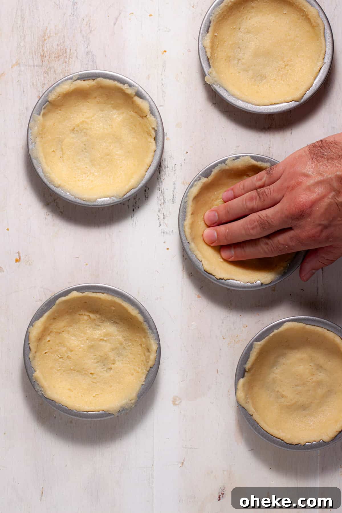 A simple cookie pie crust getting pressed into mini pie pans.