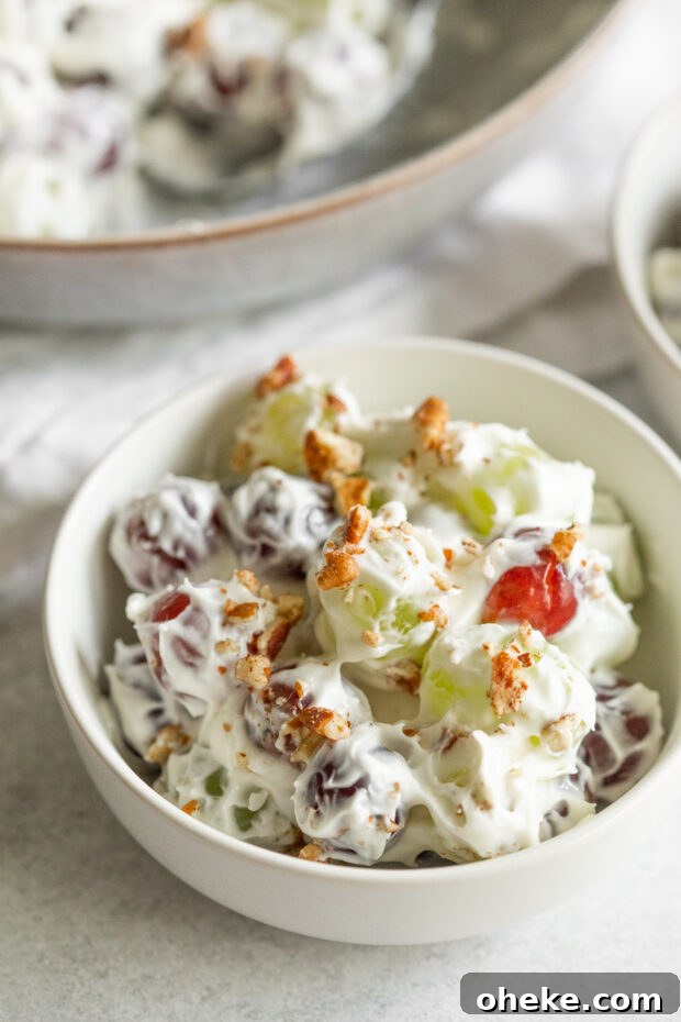 Creamy and sweet grape salad in a bowl topped with chopped pecans. 