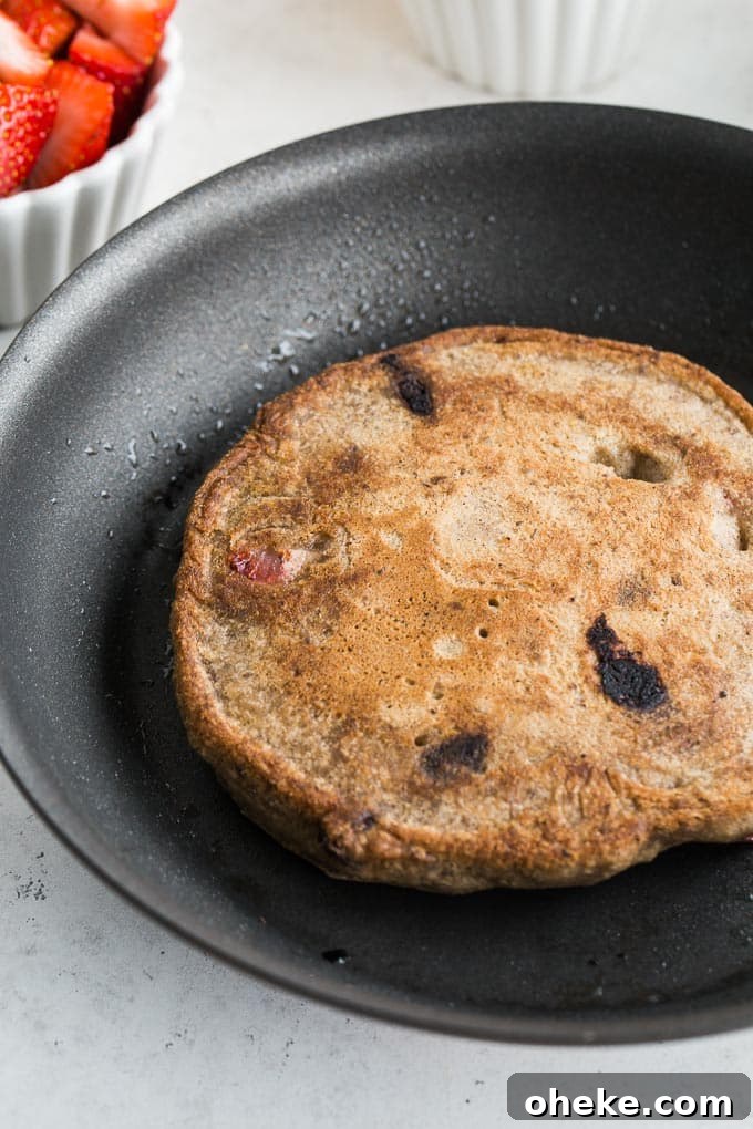 Strawberry Chocolate Chip Buckwheat Pancakes Recipe 7 Up-close view of a Strawberry Chocolate Chip Buckwheat Pancake fully cooked in a skillet.