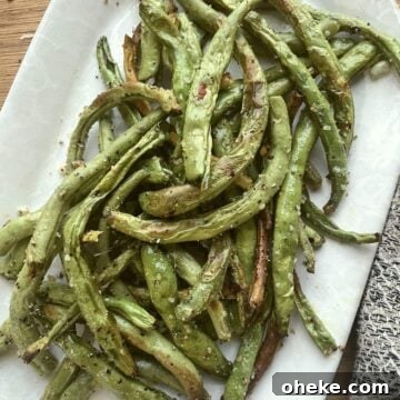 Crispy Garlic Air Fryer Green Beans_recipe 8 Seasoned air fried green beans on a white plate.