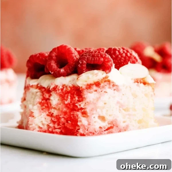 A slice of White Raspberry Poke Cake on a white plate topped with fresh raspberries and chopped almonds. More slices on plates in the background.