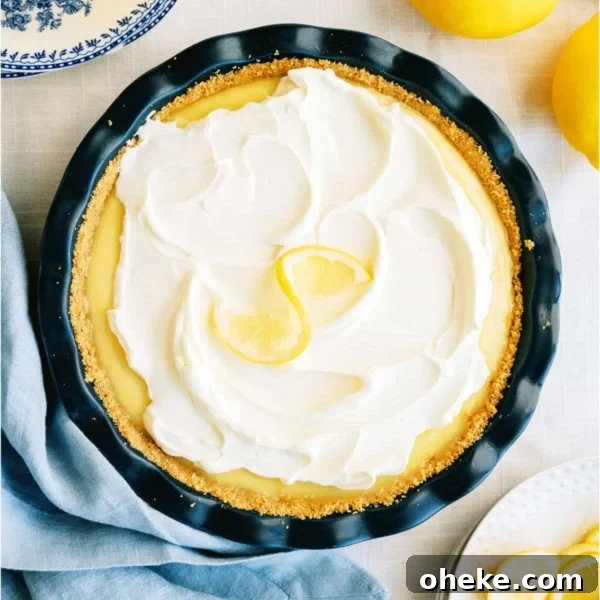 Top view of creamy lemon pie with fresh lemons in the background.