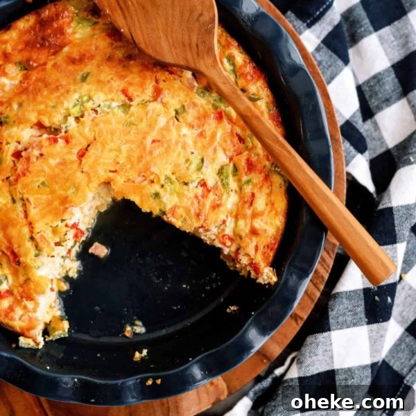 A partially eaten vegetable quiche in a round dish, placed on a wooden board with a wooden spatula on top, next to a black and white checkered cloth.