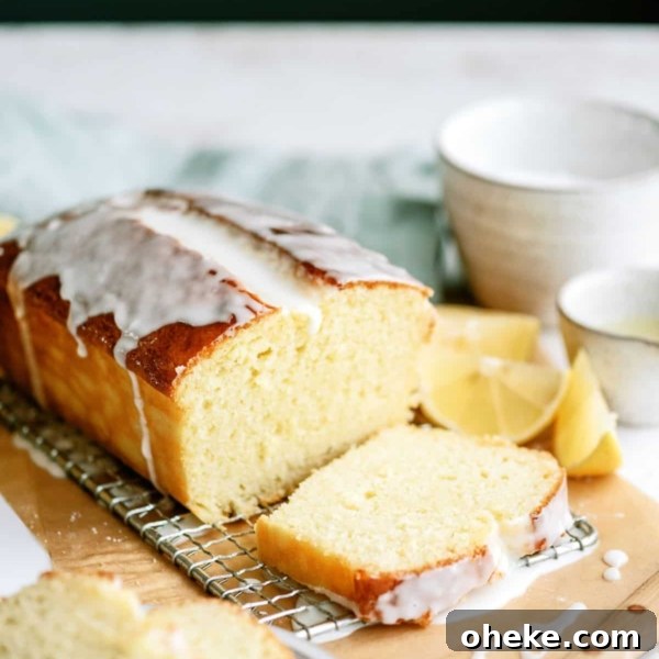 A loaf of Lemon Yogurt Bread on a cutting board with the loaf partially sliced.