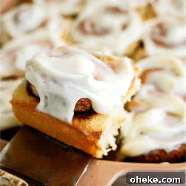 A pan of Classic Cinnamon Rolls with a spatula lifting one out