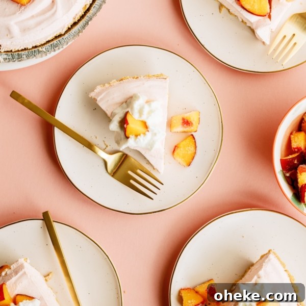Five slices of peach pie topped with whipped cream and peach chunks are served on plates with gold forks, arranged on a peach-colored surface.