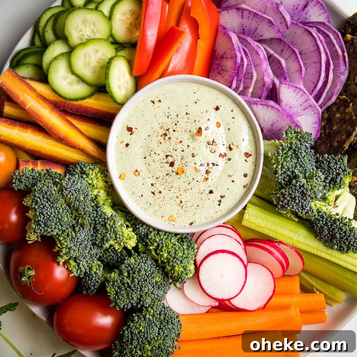 Vegan ranch in a small bowl in the center of the photo, surrounded by colorful but up veggies.