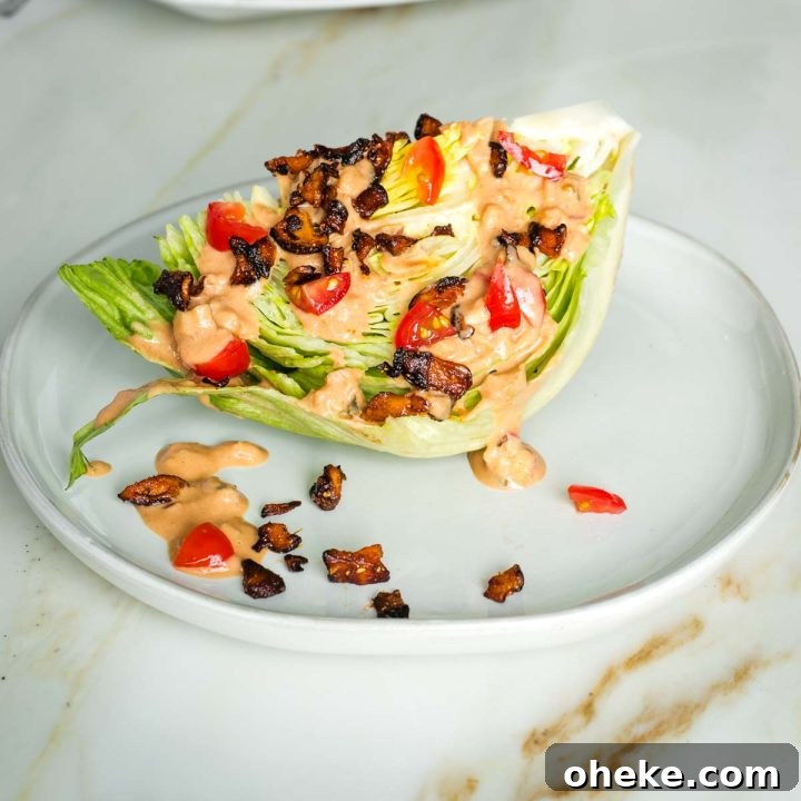 Wedge of iceberg lettuce with russian dressing, vegan bacon crumbles and diced tomatoes.