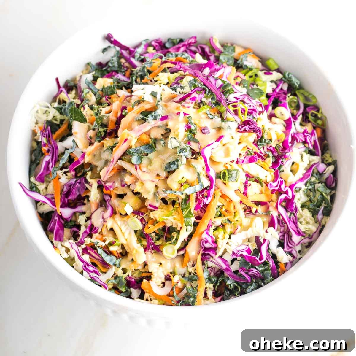 Large bowl with colorful cabbage, carrots, kale and a creamy dressing.