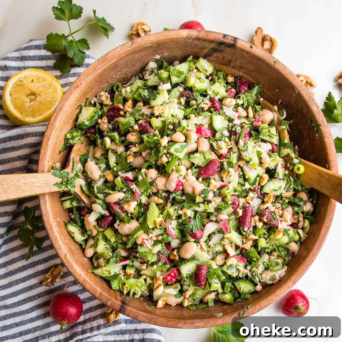 wooden bowl filled with bean salad including kidney beans, white beans, lots of green and radishes.