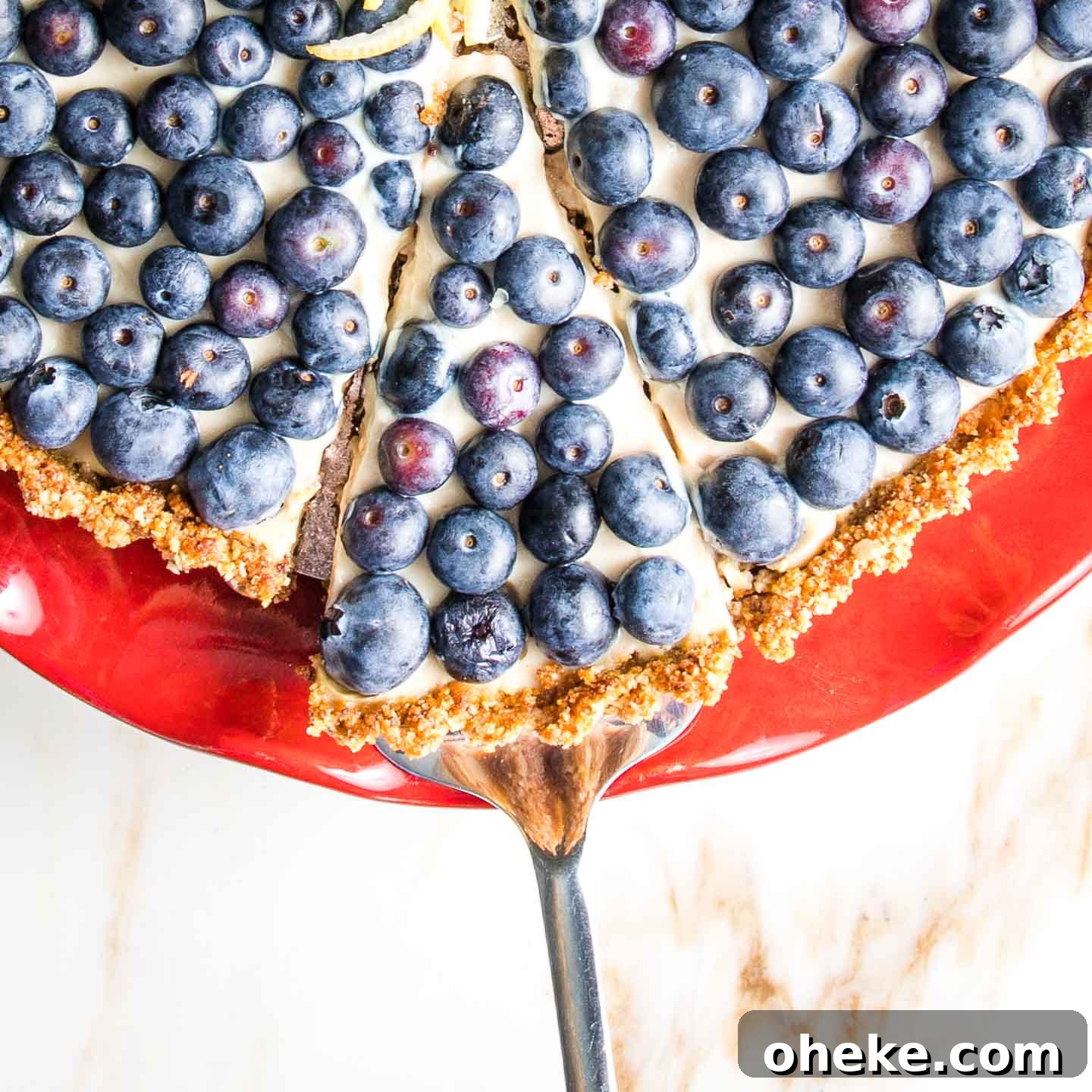 A slice of blueberry tart being served from a red cake plate.