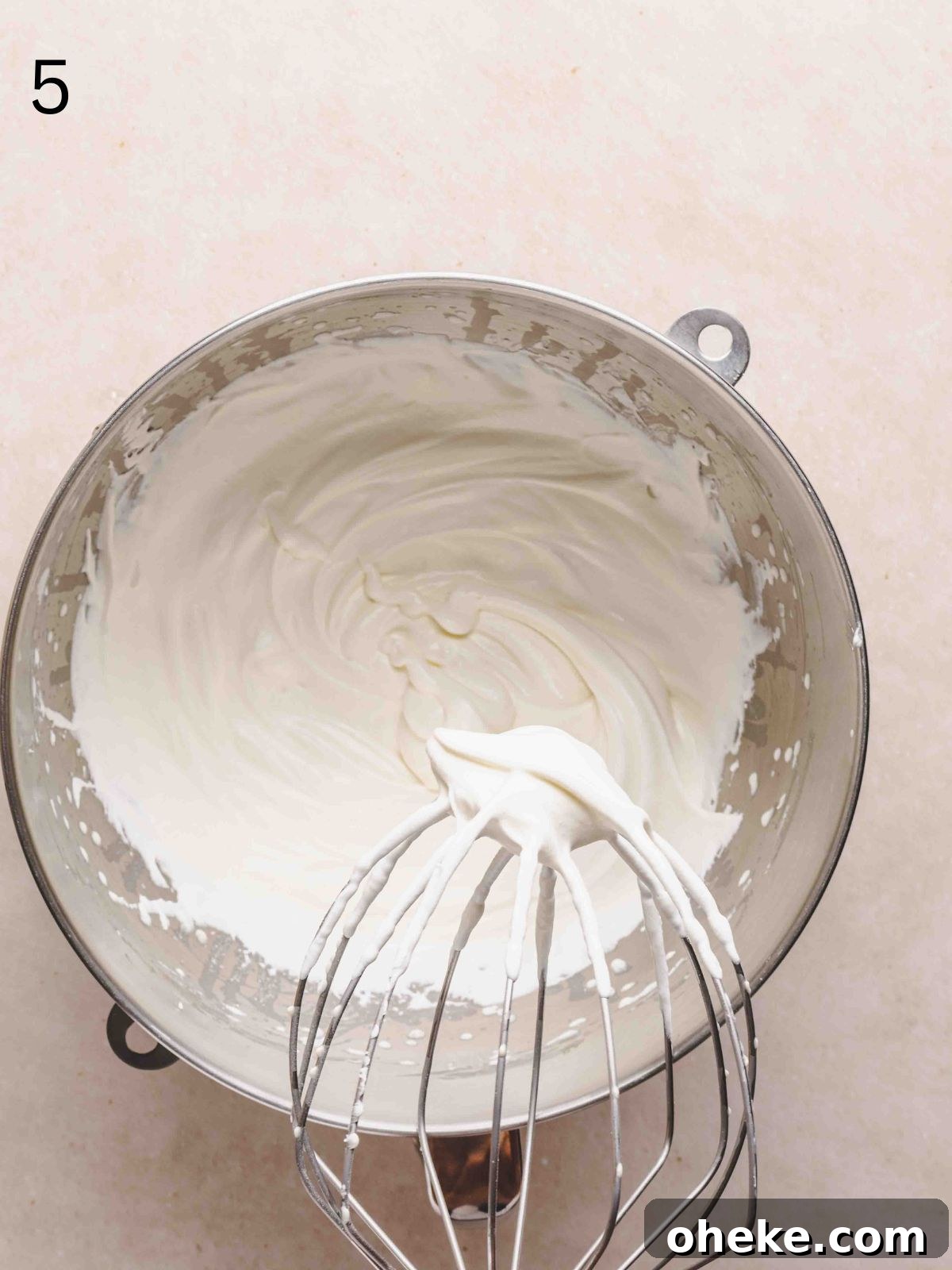 Whipped cream in a mixing bowl showing medium peaks.