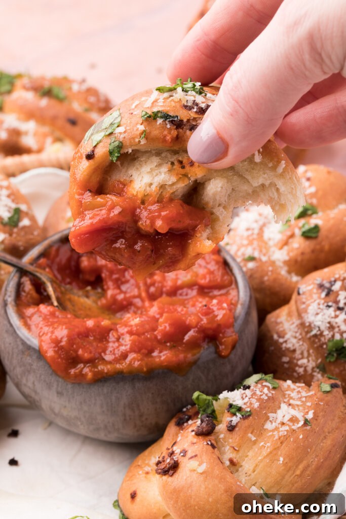 Homemade Garlic Knot Recipe: Soft, Chewy Garlic Bread Knots 4 garlic knot being dipped into tomato sauce