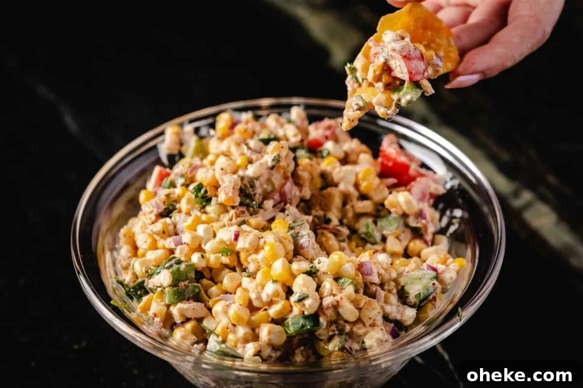 How to Store, Reheat, and Repurpose BBQ Leftovers 17 A large glass bowl full of corn dip, and a hand holding a chip with a scoop of the dip above the bowl.