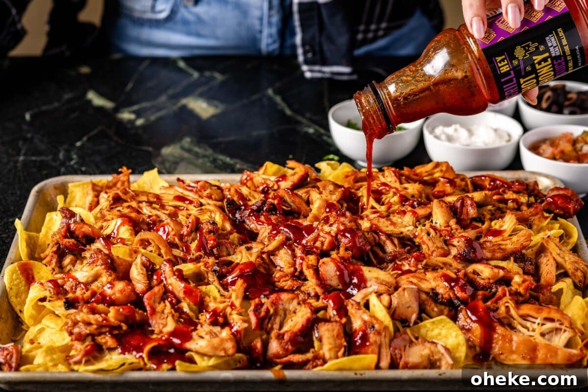 How to Store, Reheat, and Repurpose BBQ Leftovers 7 A baking sheet of nachos being drizzled with BBQ sauce.